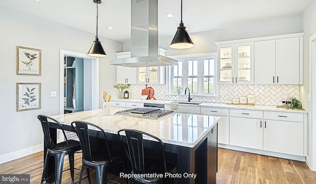 kitchen with white cabinets, island exhaust hood, light hardwood / wood-style floors, and a kitchen island