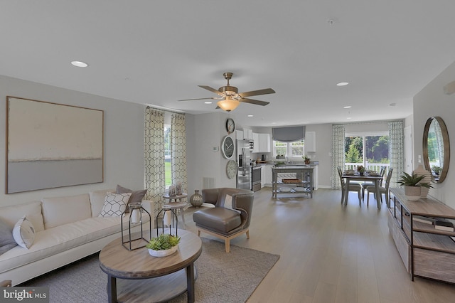 living room with ceiling fan and light wood-type flooring