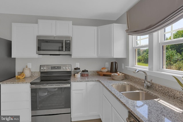 kitchen with appliances with stainless steel finishes, light stone counters, white cabinetry, and sink