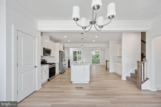 kitchen with white cabinets, hanging light fixtures, a kitchen island with sink, stainless steel appliances, and decorative backsplash