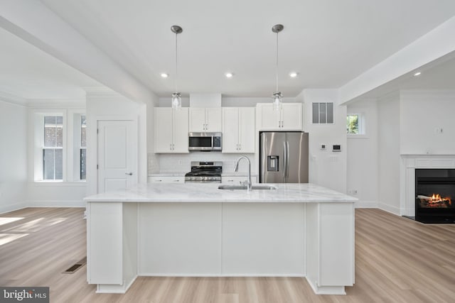 kitchen featuring appliances with stainless steel finishes, sink, hanging light fixtures, white cabinets, and a large island