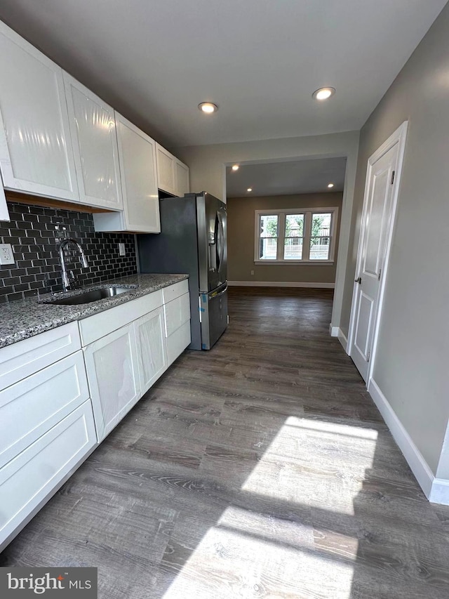 kitchen with decorative backsplash, dark hardwood / wood-style floors, sink, white cabinetry, and stone countertops