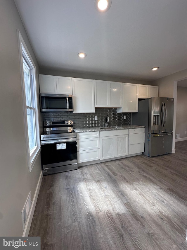 kitchen featuring stainless steel appliances, plenty of natural light, and white cabinetry