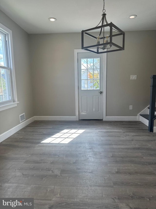 unfurnished dining area with a notable chandelier, dark hardwood / wood-style flooring, and a healthy amount of sunlight