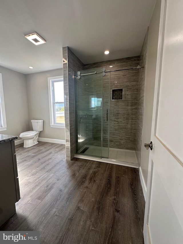 bathroom featuring hardwood / wood-style flooring, vanity, a shower with door, and toilet