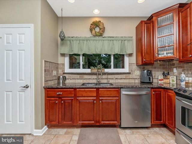 kitchen with hanging light fixtures, sink, backsplash, appliances with stainless steel finishes, and dark stone counters