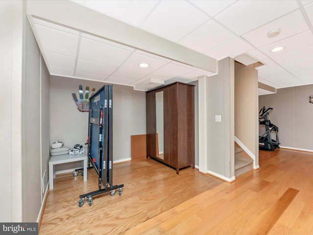 workout area featuring a drop ceiling and hardwood / wood-style floors