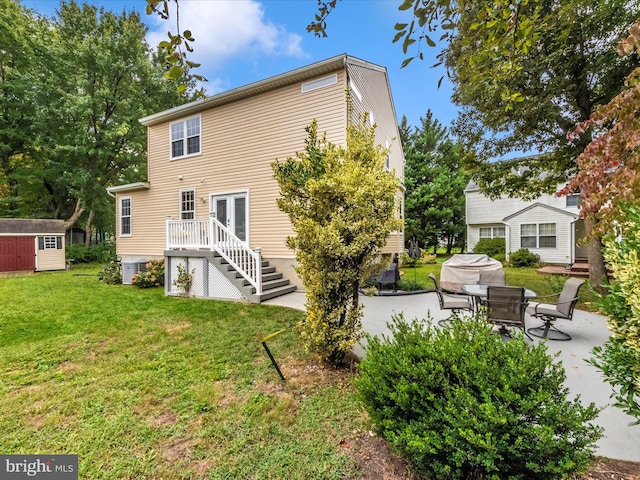 rear view of property with a storage unit, a lawn, and a patio