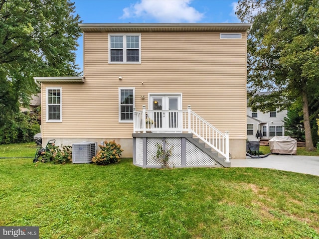 back of property featuring central AC unit and a lawn