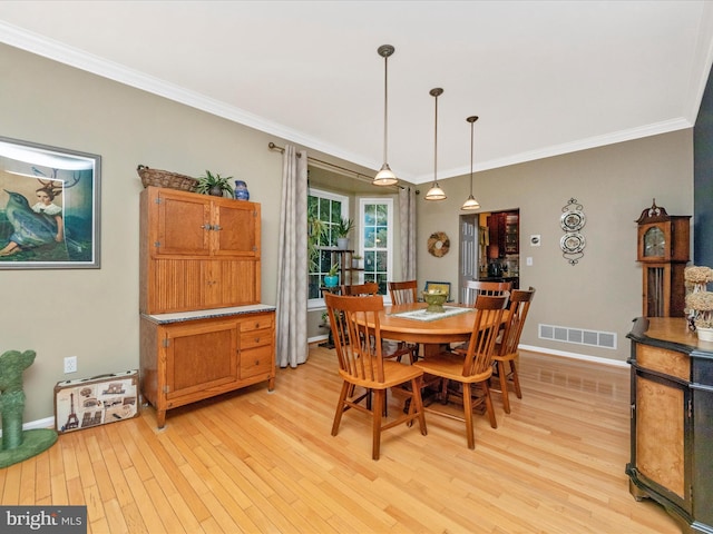 dining space with light hardwood / wood-style floors and ornamental molding