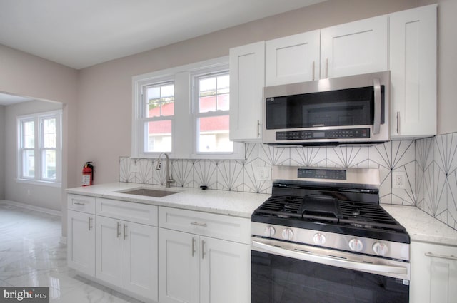 kitchen with appliances with stainless steel finishes, white cabinetry, decorative backsplash, and sink