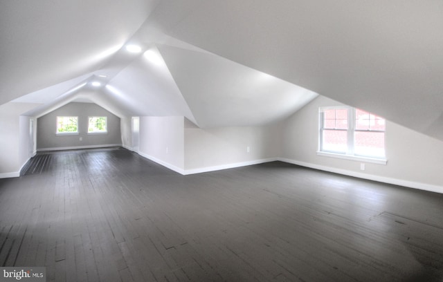 bonus room with dark hardwood / wood-style floors and vaulted ceiling