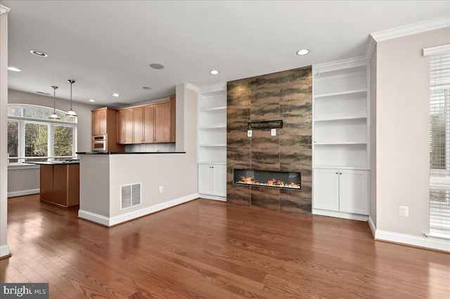 unfurnished living room featuring a fireplace, crown molding, built in shelves, and dark hardwood / wood-style floors