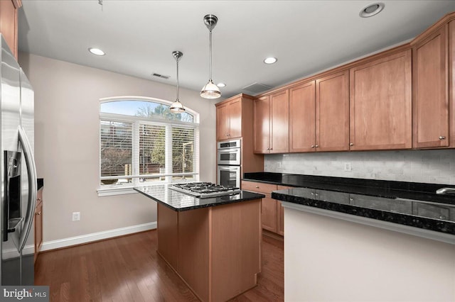 kitchen featuring a kitchen island, decorative light fixtures, appliances with stainless steel finishes, dark hardwood / wood-style floors, and dark stone countertops