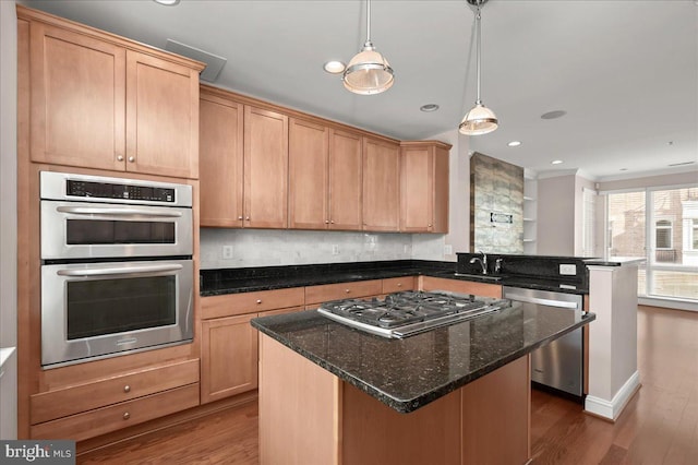 kitchen with pendant lighting, stainless steel appliances, a center island, dark stone countertops, and dark hardwood / wood-style flooring