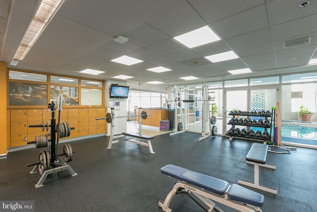 exercise room with expansive windows and a paneled ceiling