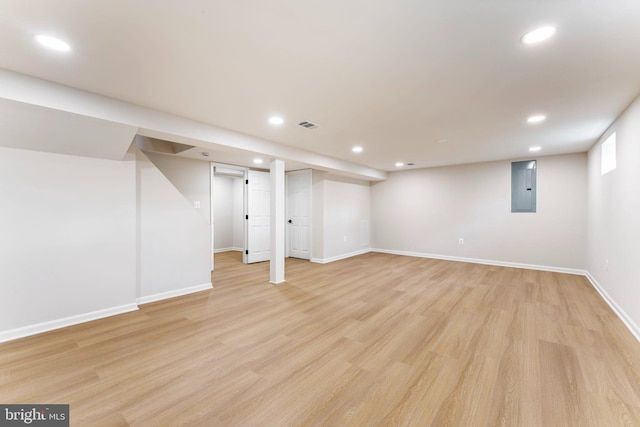 basement with electric panel and light hardwood / wood-style floors