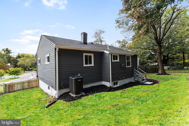 back of property with central air condition unit and a yard