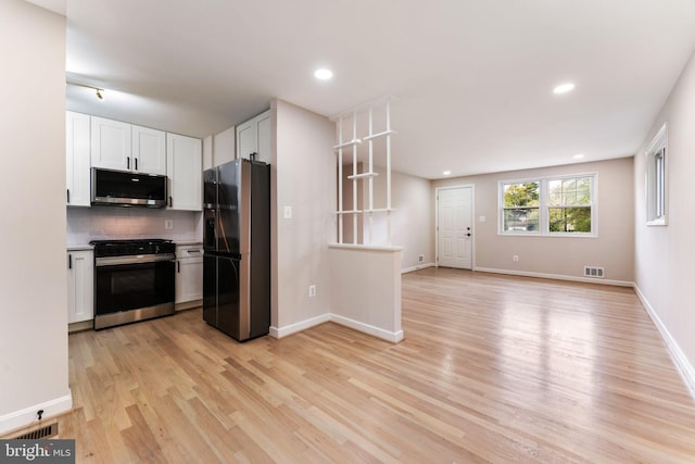 kitchen with white cabinetry, stainless steel appliances, tasteful backsplash, and light wood-type flooring