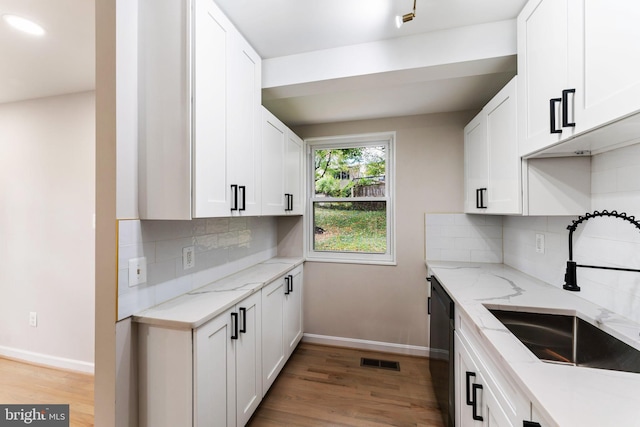 kitchen with white cabinets, backsplash, light wood-type flooring, sink, and light stone counters