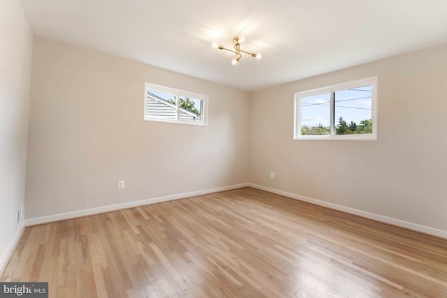 unfurnished room with light hardwood / wood-style flooring, an inviting chandelier, and plenty of natural light