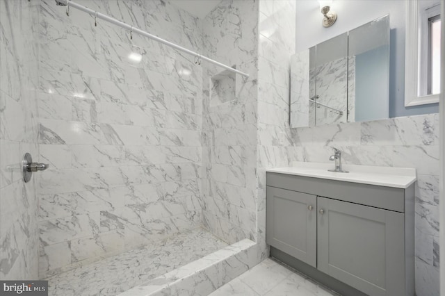 bathroom with a tile shower, tile walls, and vanity