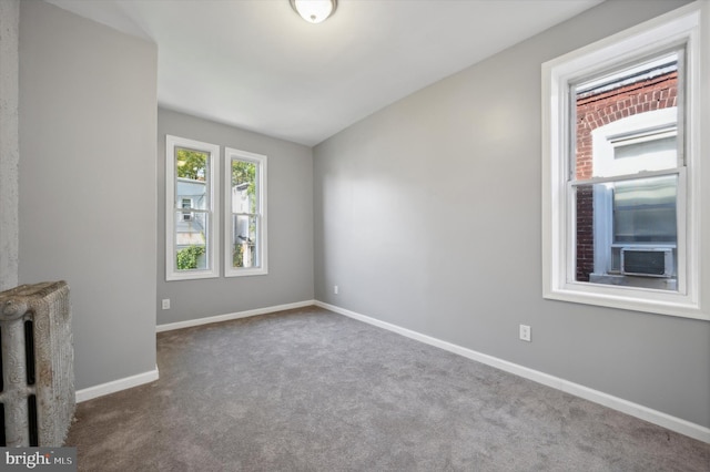 unfurnished living room featuring cooling unit, radiator heating unit, and carpet