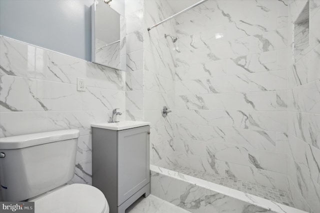 bathroom with vanity, tiled shower, toilet, and tile walls