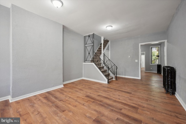 unfurnished living room featuring radiator and hardwood / wood-style floors