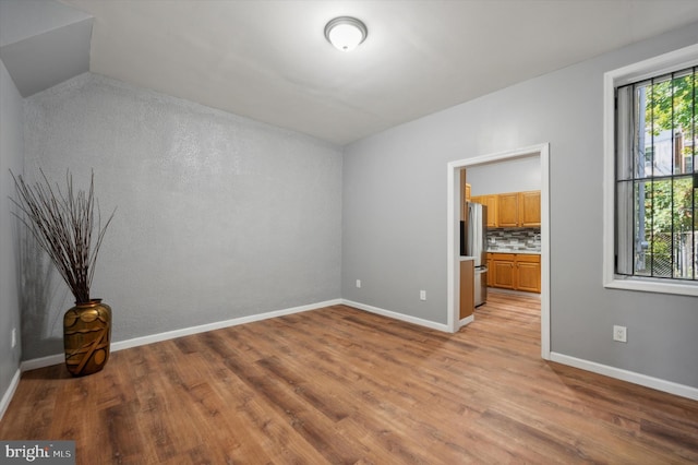 empty room featuring vaulted ceiling and light wood-type flooring