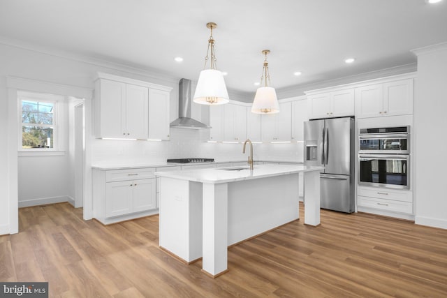 kitchen with stainless steel appliances, sink, wall chimney range hood, light hardwood / wood-style flooring, and white cabinetry