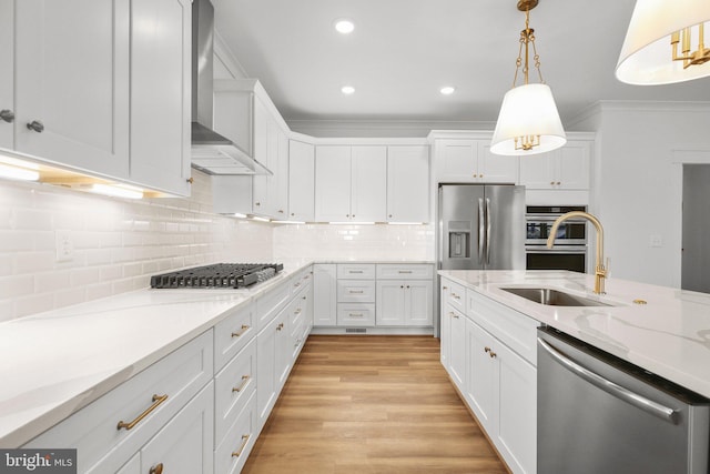 kitchen with white cabinetry, hanging light fixtures, stainless steel appliances, and wall chimney range hood