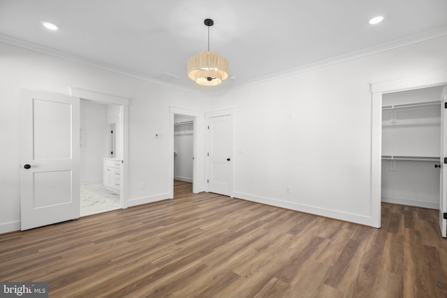 unfurnished bedroom with a walk in closet, dark hardwood / wood-style floors, and crown molding