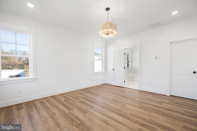 spare room with wood-type flooring, crown molding, and a notable chandelier