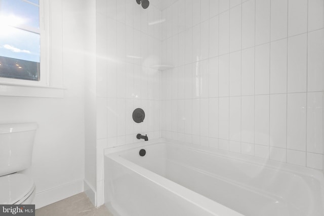 bathroom with tile patterned floors, toilet, and tiled shower / bath