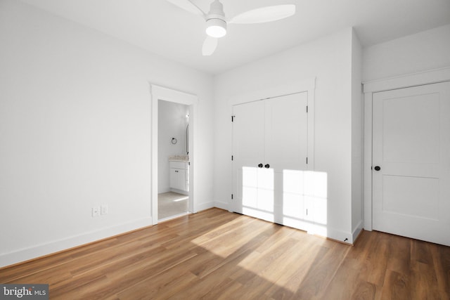 unfurnished bedroom featuring hardwood / wood-style floors, ceiling fan, a closet, and ensuite bath