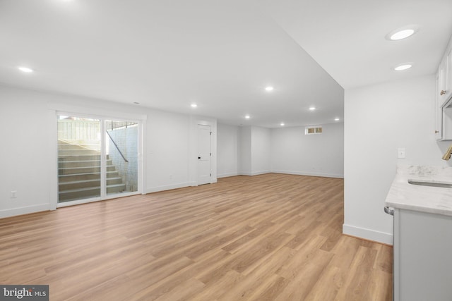 unfurnished living room featuring light hardwood / wood-style flooring and sink