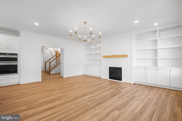 unfurnished living room with a chandelier, a fireplace, and light hardwood / wood-style flooring