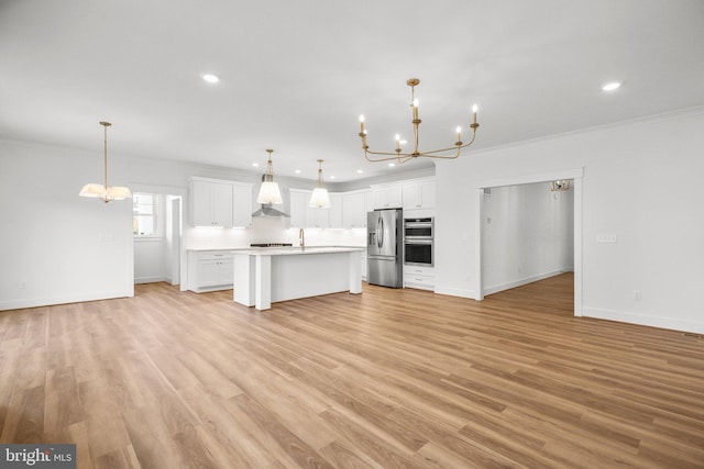 kitchen with white cabinets, appliances with stainless steel finishes, light wood-type flooring, and decorative light fixtures