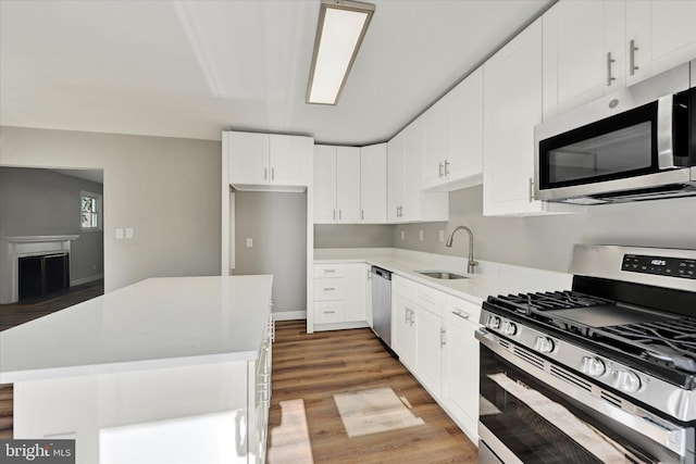 kitchen featuring appliances with stainless steel finishes, sink, a center island, light hardwood / wood-style floors, and white cabinets