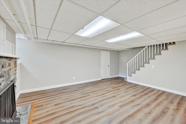 basement featuring a drop ceiling and light hardwood / wood-style flooring