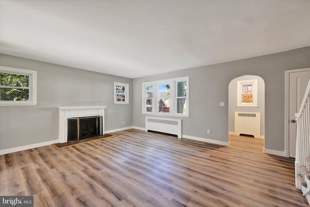 unfurnished living room featuring light hardwood / wood-style floors, radiator heating unit, and plenty of natural light