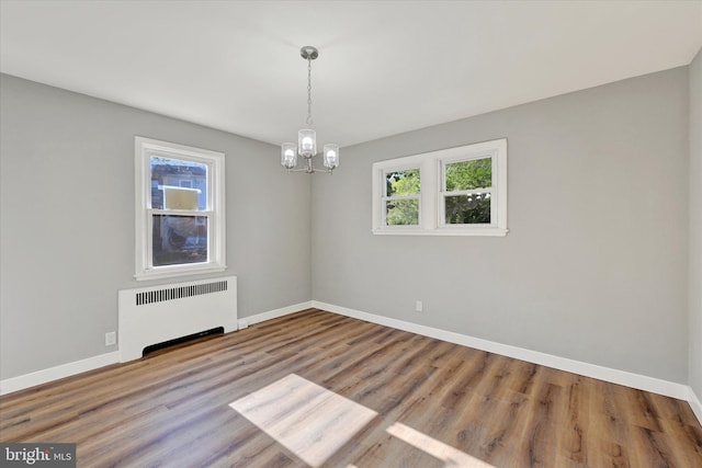 empty room featuring radiator, a wealth of natural light, and hardwood / wood-style floors