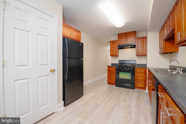 1121 Ward St, Baltimore, MD 21230 - kitchen with black appliances, under cabinet range hood, dark countertops, light wood-style flooring, and brown cabinets