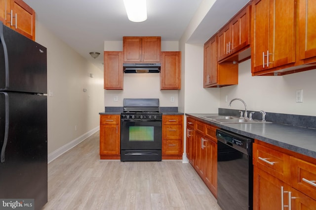 1121 Ward St, Baltimore, MD 21230 - kitchen with black appliances, under cabinet range hood, light wood-type flooring, dark countertops, and brown cabinets