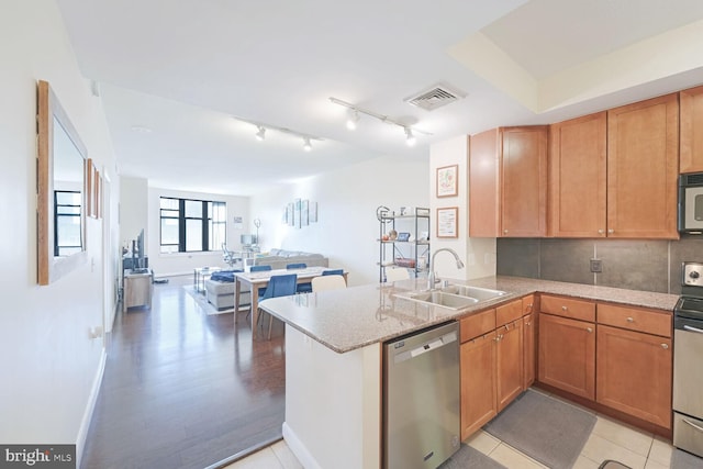 kitchen featuring kitchen peninsula, decorative backsplash, light wood-type flooring, sink, and stainless steel appliances