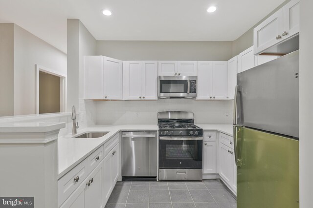 kitchen with sink, white cabinets, light tile patterned floors, appliances with stainless steel finishes, and tasteful backsplash