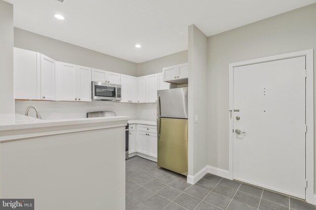 kitchen with appliances with stainless steel finishes, sink, tile patterned flooring, and white cabinets