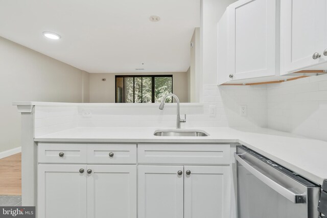 kitchen with wood-type flooring, sink, stainless steel dishwasher, white cabinetry, and tasteful backsplash