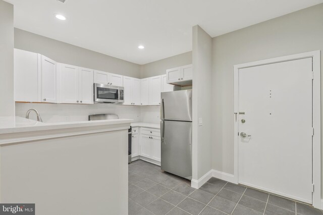 kitchen featuring appliances with stainless steel finishes, white cabinets, backsplash, and tile patterned flooring